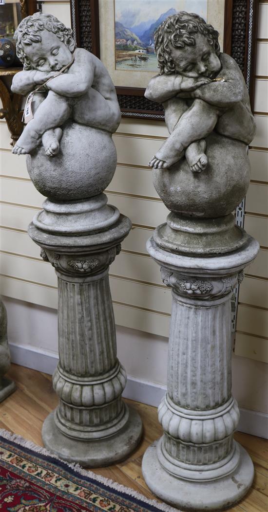 A pair of reconstituted stone columns, surmounted by putti seated on balls H.137cm